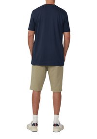 T-shirt di cotone blu navy a maniche corte abbinata a pantaloni beigi, con una consistenza morbida. Calzini bianchi e scarpe casual inclusi.