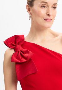 Rotes Kleid mit einem einseitigen Design und einer großen Satin-Schleifen-Akzent auf der linken Schulter. Sanfter Stoffeindruck, enganliegende Silhouette.