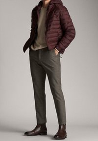 Burgundy pufferjakke med hætte, lysegrå sweater, skræddersyede grå bukser og brune læder ankelstøvler.