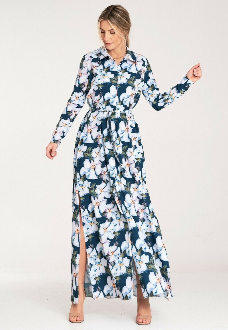 Długa sukienka maxi z długim rękawem, w kwiatowy wzór w odcieniach bieli, różu i zieleni na granatowym tle, z zapięciem na guziki z przodu i bocznymi rozcięciami.