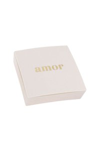 Scatola quadrata color crema con superficie liscia. La parola "amor" è impressionata in oro sulla parte superiore. Design semplice ed elegante con angoli arrotondati.