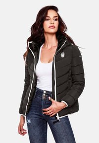 Puffer jacket, black with horizontal stitching, fur-lined hood, white zipper, embroidered logo on chest, paired with high-waisted blue jeans.