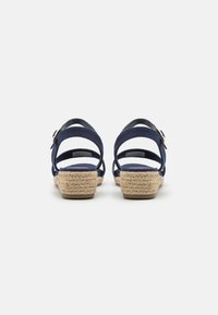 Marineblauwe espadrille sandalen met een geweven jute wiggenhak, enkelbandjes en een goudkleurige gesp. Glad stof en gestructureerde zool.