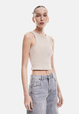 Lichtbeige geribbelde crop top met brede schouderbanden, gecombineerd met lichtblauwe hoge taille spijkerbroeken, met een losse pasvorm en vervaagde textuur.