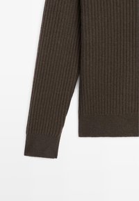 Dettaglio delle maniche e dell'orlo inferiore di un maglione a coste di colore marrone scuro su sfondo bianco.