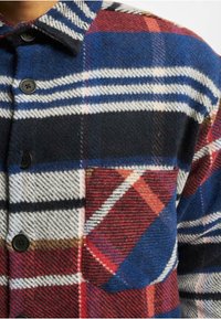 Košile-jacket z vlněné směsi s vícebarevným károvaným vzorem v modré, červené, bílé a černé barvě, s černými knoflíky a náprsní kapsou.