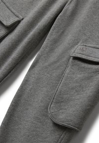 Szare spodnie cargo wykonane z miękkiego materiału, z bocznymi kieszeniami, w luźnym kroju oraz detalami w postaci przeszyć. Gładka tekstura z niewielką elastycznością.