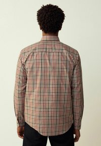 Camicia a maniche lunghe a quadri con una combinazione di controlli rossi, verdi e beige, polsini con bottoni e orlo curvo. Vista posteriore con dettagli delle cuciture.