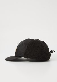 Cappellino nero con visiera curva, dotato di un morbido rivestimento in pile nero texturizzato sui lati e di una fascia di regolazione posteriore.