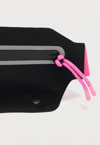 Accessoire en néoprène noir avec une bande grise et un cordon rose. Il présente un accent noir brillant et un design à bords arrondis pour un ajustement sûr.