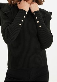 Czarny, prążkowany top z długim rękawem, z falbankami na ramionach oraz złotymi guzikami na mankietach, teksturowana tkanina i dopasowany fason.
