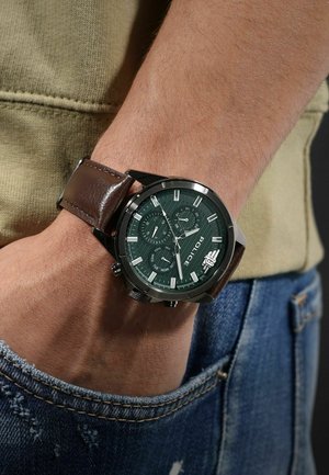 Montre pour homme avec un cadran vert, boîtier en acier inoxydable et bracelet en cuir brun. Les caractéristiques incluent trois sous-cadrans et des index d'heure blancs.