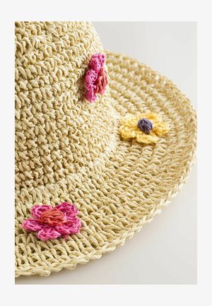 Platus šiaudinis skrybėlė smėlio spalvos, papuošta rožinėmis, oranžinėmis ir geltonomis gėlėmis, demonstruojanti austo tekstūrą ir apvalią formą.