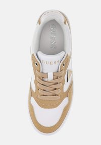 Sneaker bianca e beige con tomaia in pelle texturizzata, chiusura con lacci e dettaglio del logo. Presenta una linguetta imbottita e una soletta morbida.