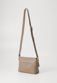 Sac bandoulière en cuir tan avec une surface texturée, comprenant une poche avant, une sangle ajustable et des accents en métal doré.