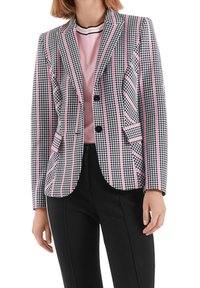 Czarnobiała marynarka w desenie houndstooth z różowymi paskami, jednorzędowy design, dwie przednie kieszenie i klapy z wycięciem. Połączona z różową bluzką.