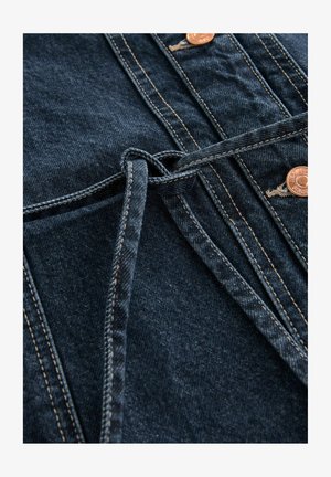 Dunkelblaues Denim-Gewebe mit einer strukturierten Oberfläche, ausgestattet mit Kupferknöpfen und einem gebundenen Gürtel-Detail, das dicke Nähte und ein strukturiertes Design zeigt.