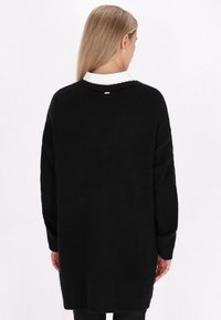Schwarzer, oversized Pullover aus weichem Strickmaterial. Mit entspannter Passform, überschnittenen Schultern und rundem Halsausschnitt. Schlichtes Design, keine sichtbaren Muster.