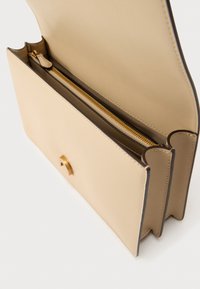 Μπεζ δερμάτινη τσάντα με απαλό υφή, ανοιχτό πάνω μέρος και χρυστό φερμουάρ. Διαθέτει καμπύλες άκρες και κλείσιμο με πόρπη στο μπροστινό μέρος.