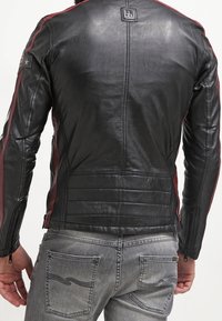 Sort lædermotorcykeljakke med røde striber, paneldetaljer og lynlåslukning. Indeholder stjerne- og mærkelogoaccenter.