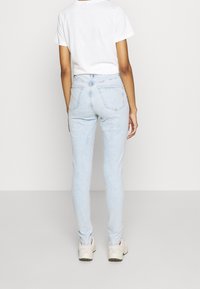 Jeans skinny de denim azul claro con cintura alta, que presentan un clásico diseño de cinco bolsillos y un ligero desvanecimiento en toda la prenda.