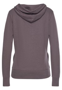 Sweat à capuche violet à manches longues, avec un cordon de serrage, des fentes sur les côtés, et des poignets et un ourlet côtelés. Fabriqué en tissu doux et texturé.