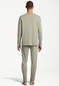 Light green long-sleeve top and matching pants made from soft, textured fabric. Simple design with a relaxed fit and no visible patterns.
