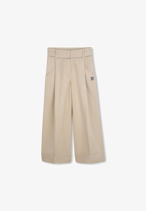 Beige broek met wijde pijpen, voorzakken, omgeslagen pijpen en contrasterende stiksels. Heeft een logopatch aan de zijkant bij de tailleband.