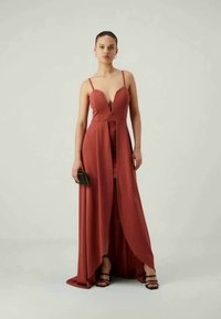 Φόρεμα βραδινής ένδυσης σε κοκκινωπό χρώμα με βαθύ ντεκολτέ, λεπτές τιράντες και ψηλή σχισμή; λείο ύφασμα με κομψό, ρευστό σχέδιο.