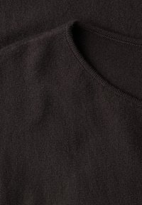 Gros plan sur un tissu tricoté gris foncé montrant la texture et une couture courbée ou un détail d'encolure.