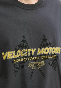 Sort bomulds t-shirt med et gult og sort grafisk design med teksten "Velocity Motors Sonic Pace Circuit" og krydsede ternede flag.