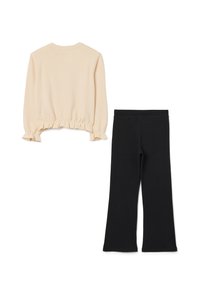 Blusa de manga larga color beige claro con dobladillo fruncido y pantalones negros de campana. La blusa tiene un escote redondo y una textura de tejido suave.