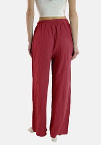Rode, gestructureerde, wijde broek met een elastische tailleband. De stof heeft een gekreukt uiterlijk, geschikt voor casual wear.