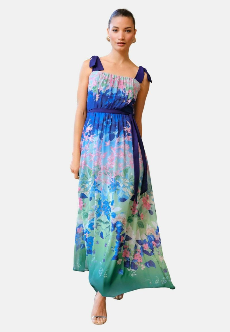 Kwiatowa sukienka maxi z dopasowanym niebieskim górnym części, falbaniastymi ramiączkami oraz zwiewną, przezroczystą spódnicą w odcieniach niebieskiego, zielonego i różowego. Oferuje pasujący pasek.