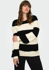 Crna i krema prugasta sweatshirt, rebrasta tekstura, dugi rukavi s lepršavim manžetama, okrugli izrez, uparen s crnim hlačama.