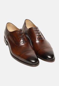 Scarpe eleganti da uomo in pelle marrone, con finitura liscia, punta affusolata, dettaglio della punta a cappuccio e design con sei occhielli per lacci. Stile classico con un sottile lucido.
