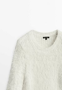 Pull en maille gris clair et duveteux avec un col rond. Présente une texture côtelée le long des manches et des épaules, avec une finition douce et brossée.