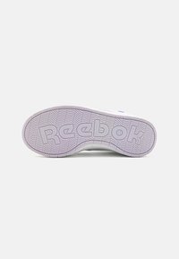 Bela podplata športnega copata z teksturiranim vijoličnim gumijastim dnom. V središču je oblikovana oznaka "Reebok" in valovite pnevmatike za boljši oprijem.