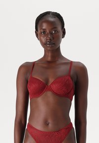 Rød bh med underwire og teksturert blomstermønster, justerbare tynne stropper og glatt overflate. Sammen med en matchende truse.