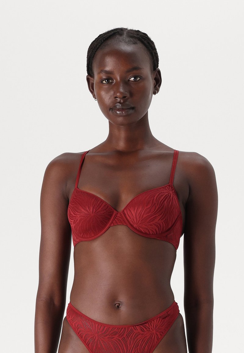 Rød bh med underwire og teksturert blomstermønster, justerbare tynne stropper og glatt overflate. Sammen med en matchende truse.