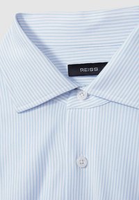 Helles, blau gestreiftes Hemd mit klassischem Kragen, Knopfverschluss und glatter Stoffstruktur. Markenetikett "REISS" sichtbar.