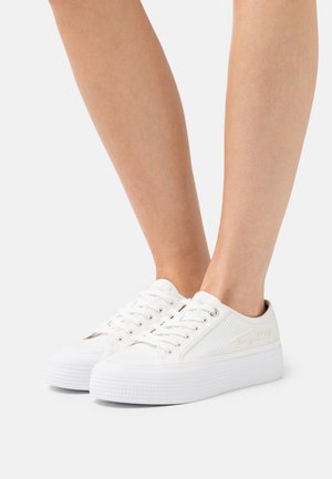 Białe trampki z teksturowaną siateczkową cholewką, płaskimi sznurowadłami i podniesioną gumową podeszwą z ozdobnym wzorem na krawędzi. Prosty design z minimalnymi akcentami.