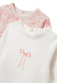 Deux tops à manches longues : l'un est écru avec un motif de nœuds roses, et l'autre est rose clair avec un motif de fleurs de cerisier. Texture en coton doux, col rond.