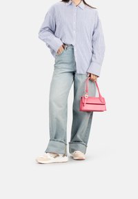 Camisa de rayas azul y blanca de gran tamaño, vaqueros de mezcla de denim claros de pierna ancha con puños deshilachados, bolso estructurado rosa y zapatillas de colores pastel.