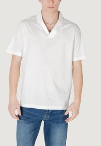 Polo shirt bianco a maniche corte con colletto a punta, realizzato in tessuto morbido, con rifiniture a contrasto lungo le maniche e l'orlo.
