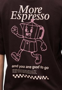 Κινούμενο μπρίκι με χέρια, πόδια και αθλητικά παπούτσια που περπατάει, με το κείμενο «Περισσότερο εσπρέσο» και «και είσαι έτοιμος» σε σκούρο μπλουζάκι.