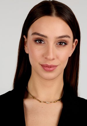 Collana choker in metallo intrecciato d'oro e d'argento con piccoli accenti decorativi, indossata su un top scuro, che mette in risalto un design elegante.