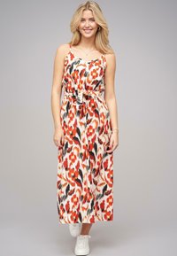 Maxime dress in a bold red, black, and white abstract pattern, featuring thin straps, a cinched waist with a tie, and a flowy silhouette.