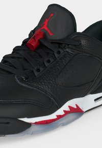 Μαύρο δερμάτινο παπούτσι Air Jordan με κόκκινες και λευκές λεπτομέρειες στη σόλα, μαύρα κορδόνια και κόκκινο λογότυπο Jumpman στη μαύρη γλώσσα και κλείδωμα κορδονιών.