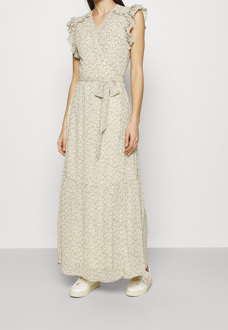 Vaaleankermanvärinen kukkakuosinen maksimekko, jossa röyhelöhihat, vyötärönauha ja kerroksittainen hame. Yhdistetty valkoisiin lenkkareihin, joissa on vaaleanpunainen yksityiskohta.